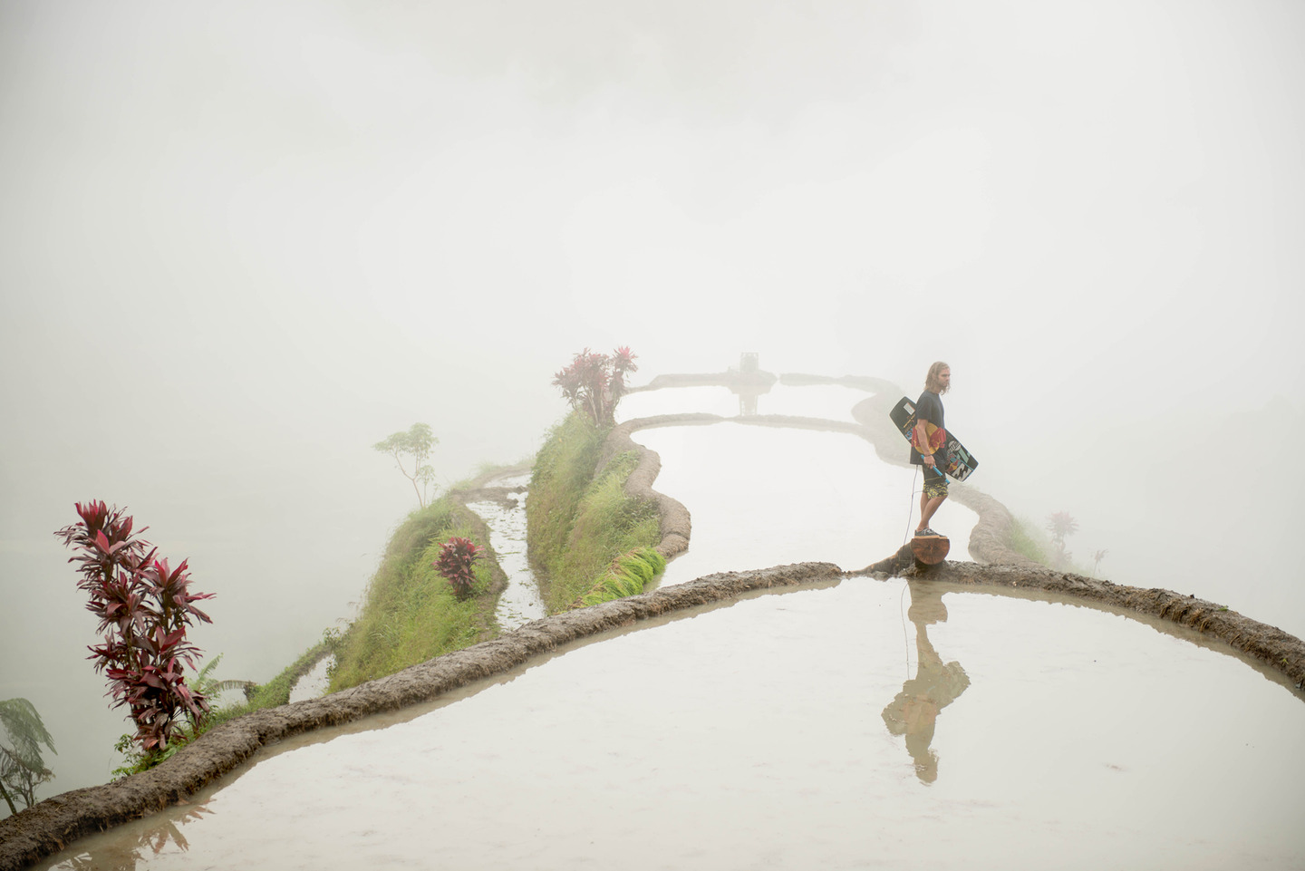 a red bull athlete is standing on the edge of a rice terrace in a foggy area