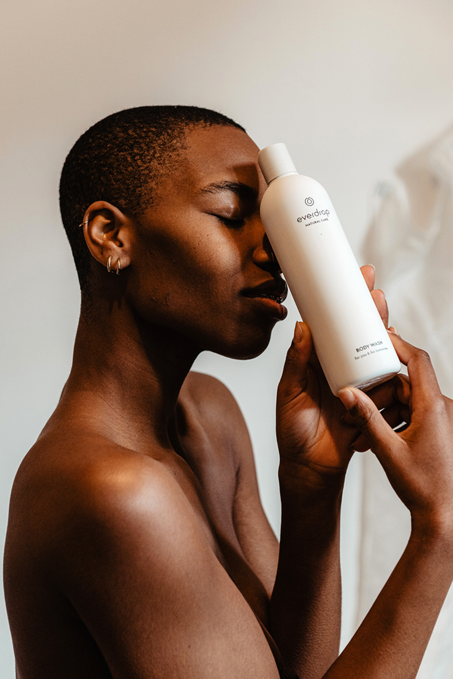 a black woman is holding a bottle of everdrop body wash