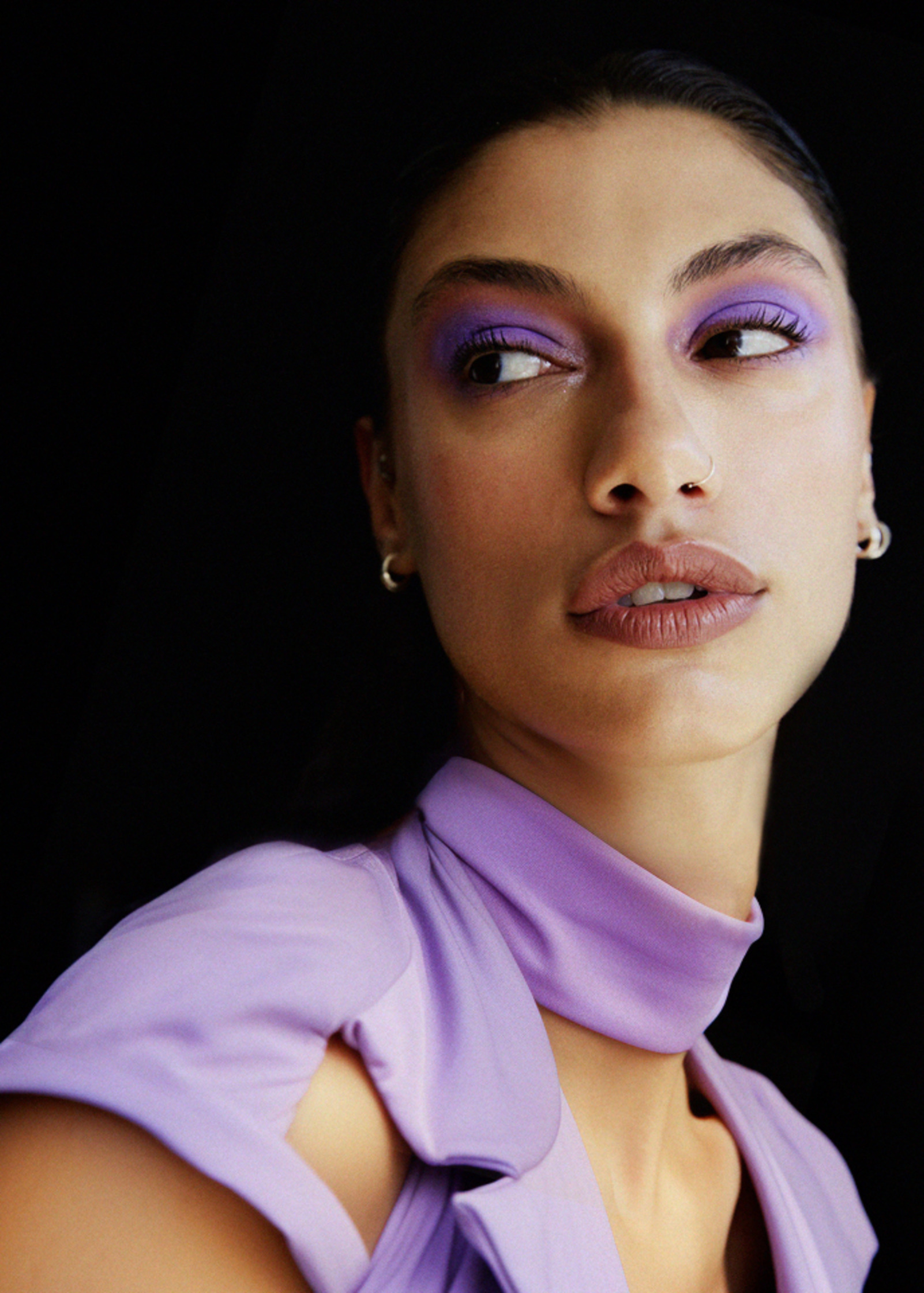 a woman wearing purple makeup and posing for a photo