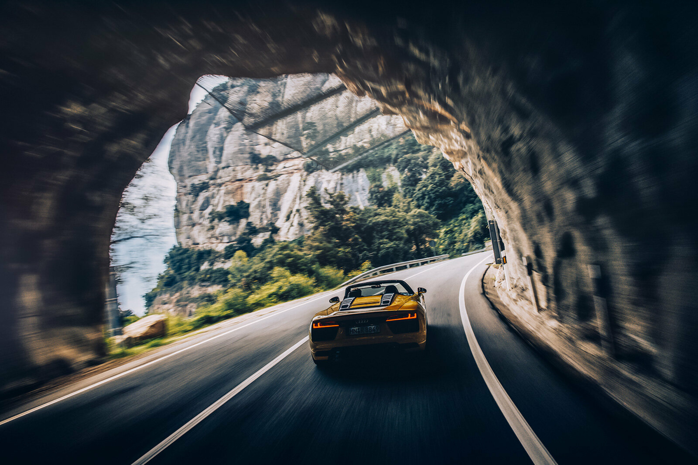 a yellow sports car driving through a tunnel