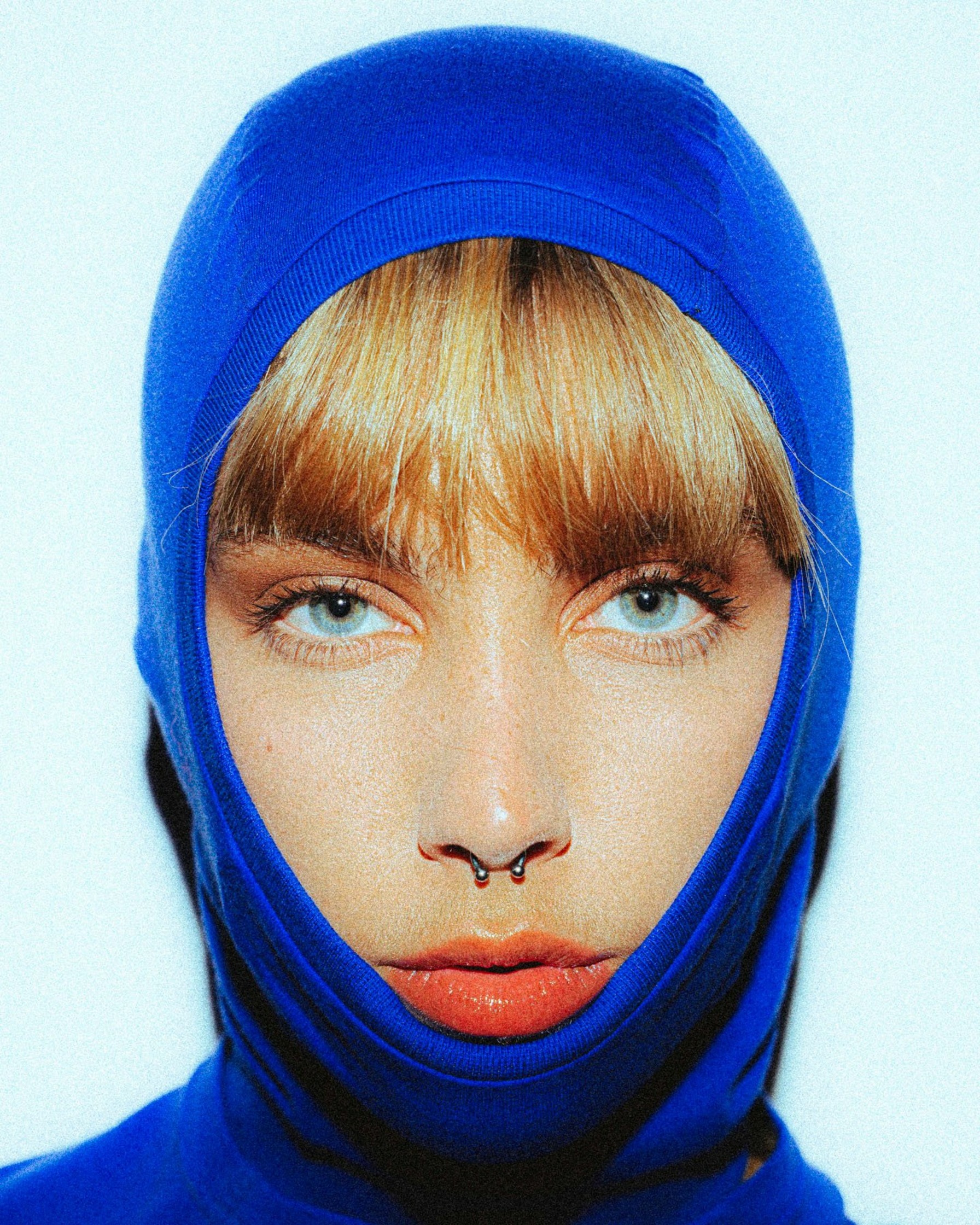 a woman in a blue hoodie with a nose piercing