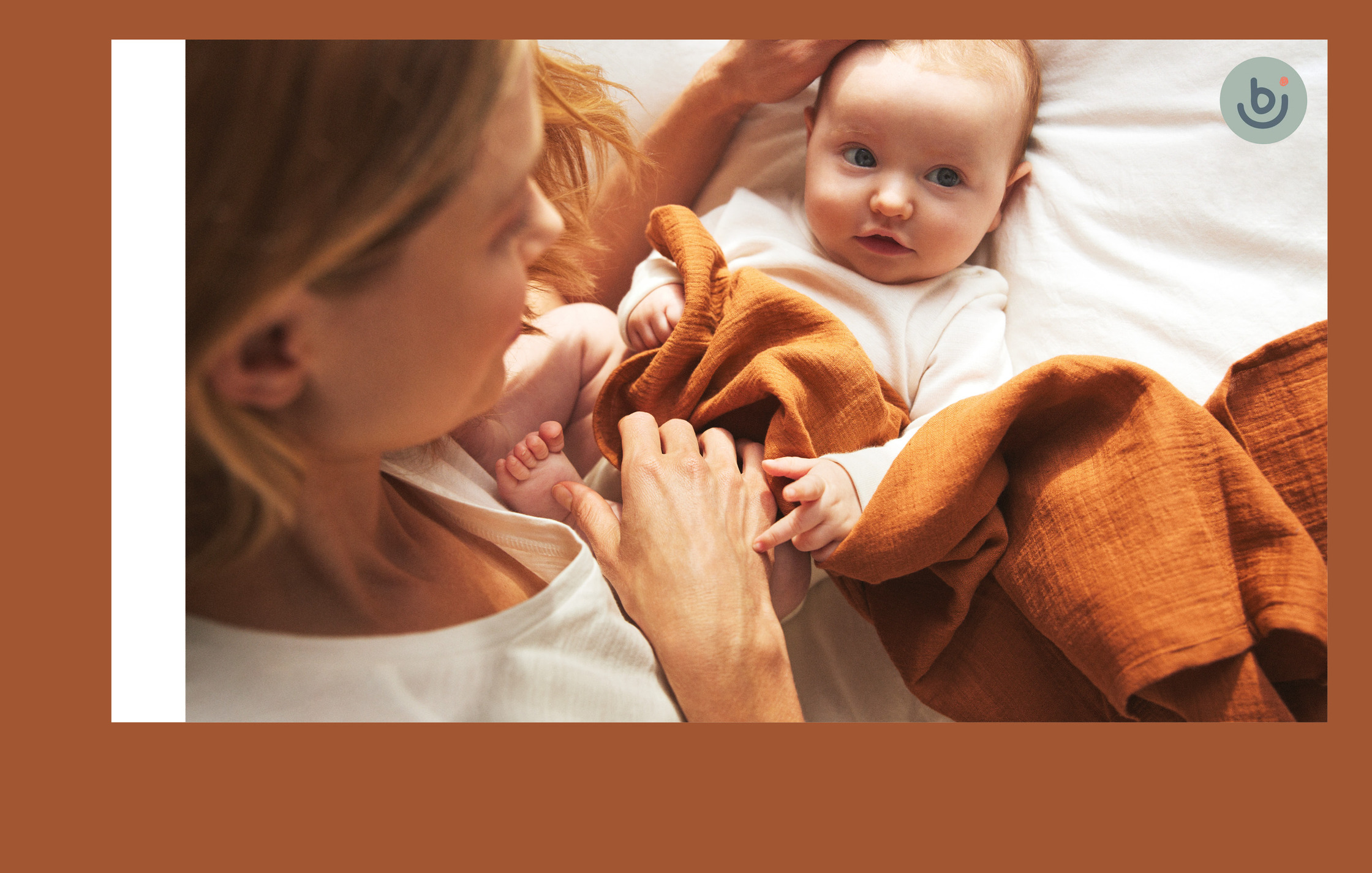 a woman is holding a baby in a bed with an orange blanket