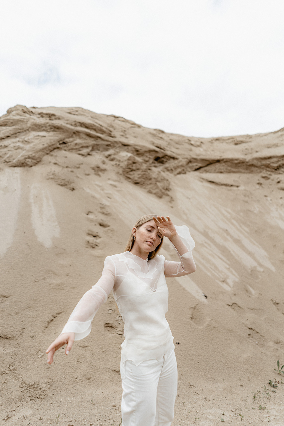 a model posing in white in front of a sand dune with maren jewellery earings