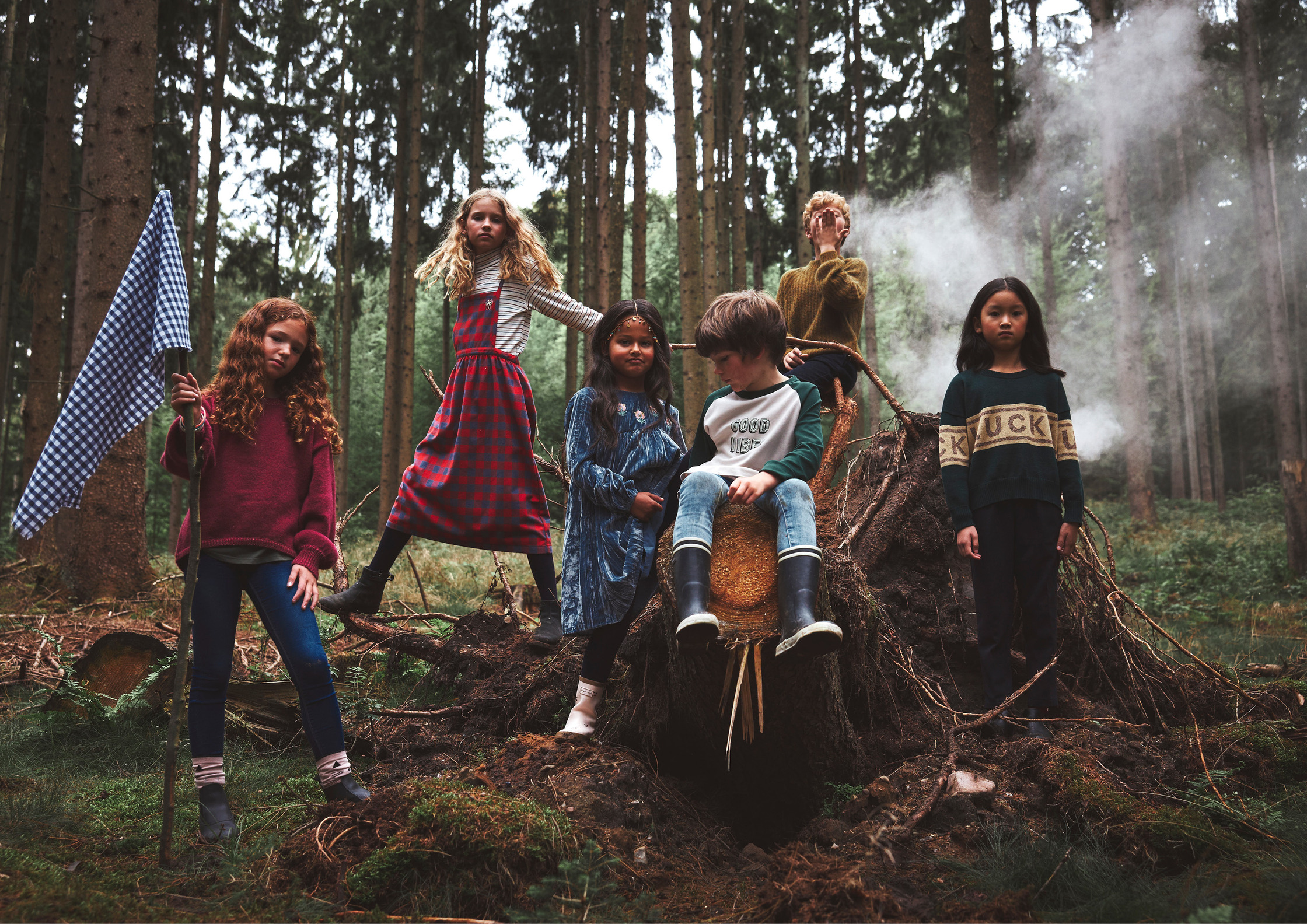 a group of children standing on top of a log in the woods