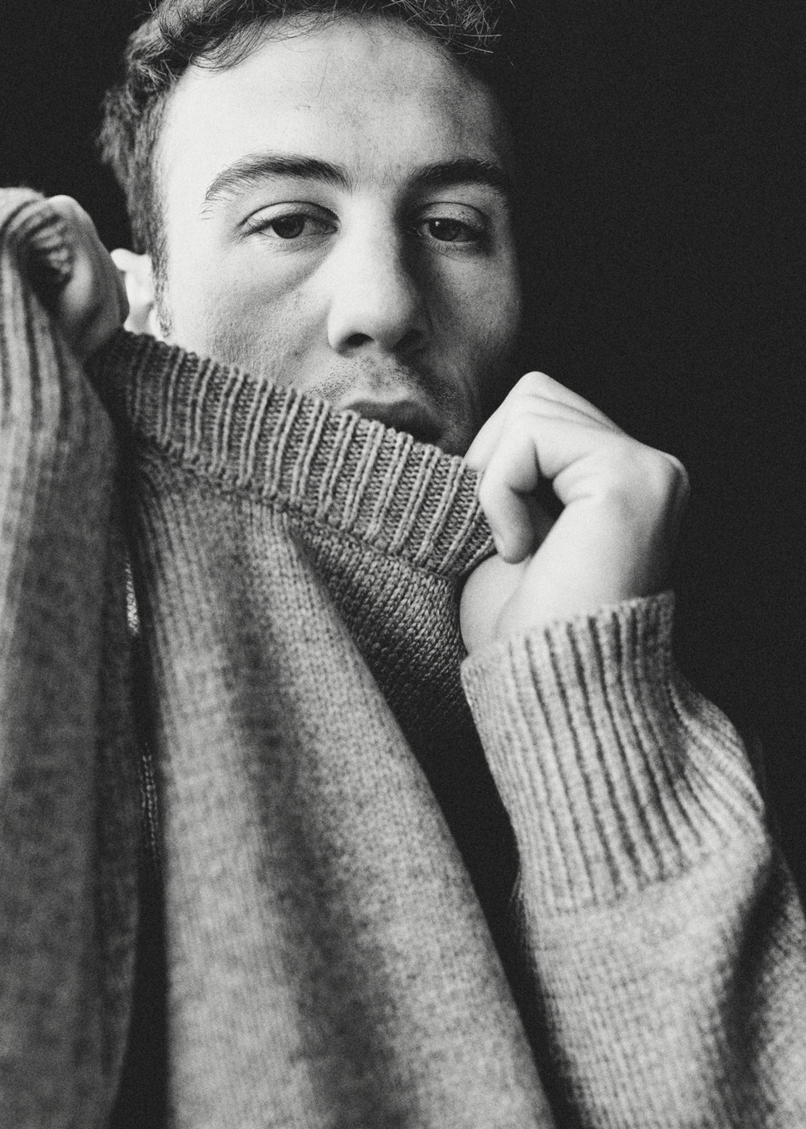 a black and white photo of a man wearing a sweater