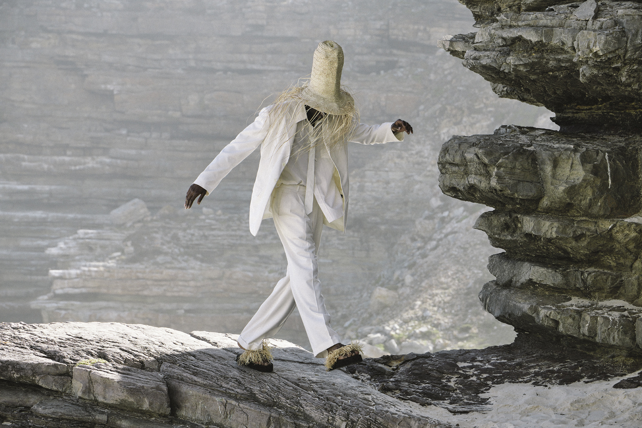 a man in a white hat walking on a rock
