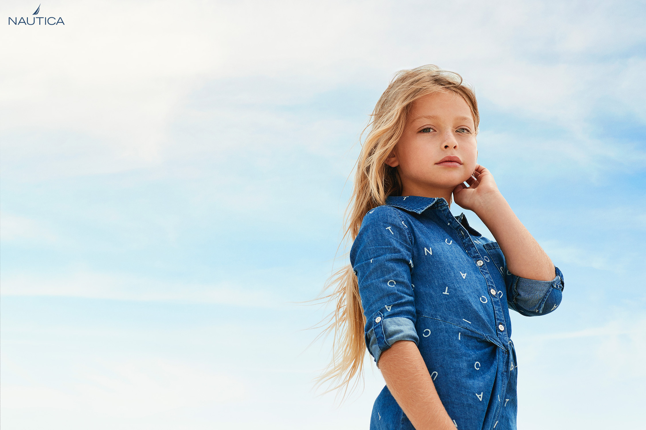 a young girl in a denim dress posing for a photo