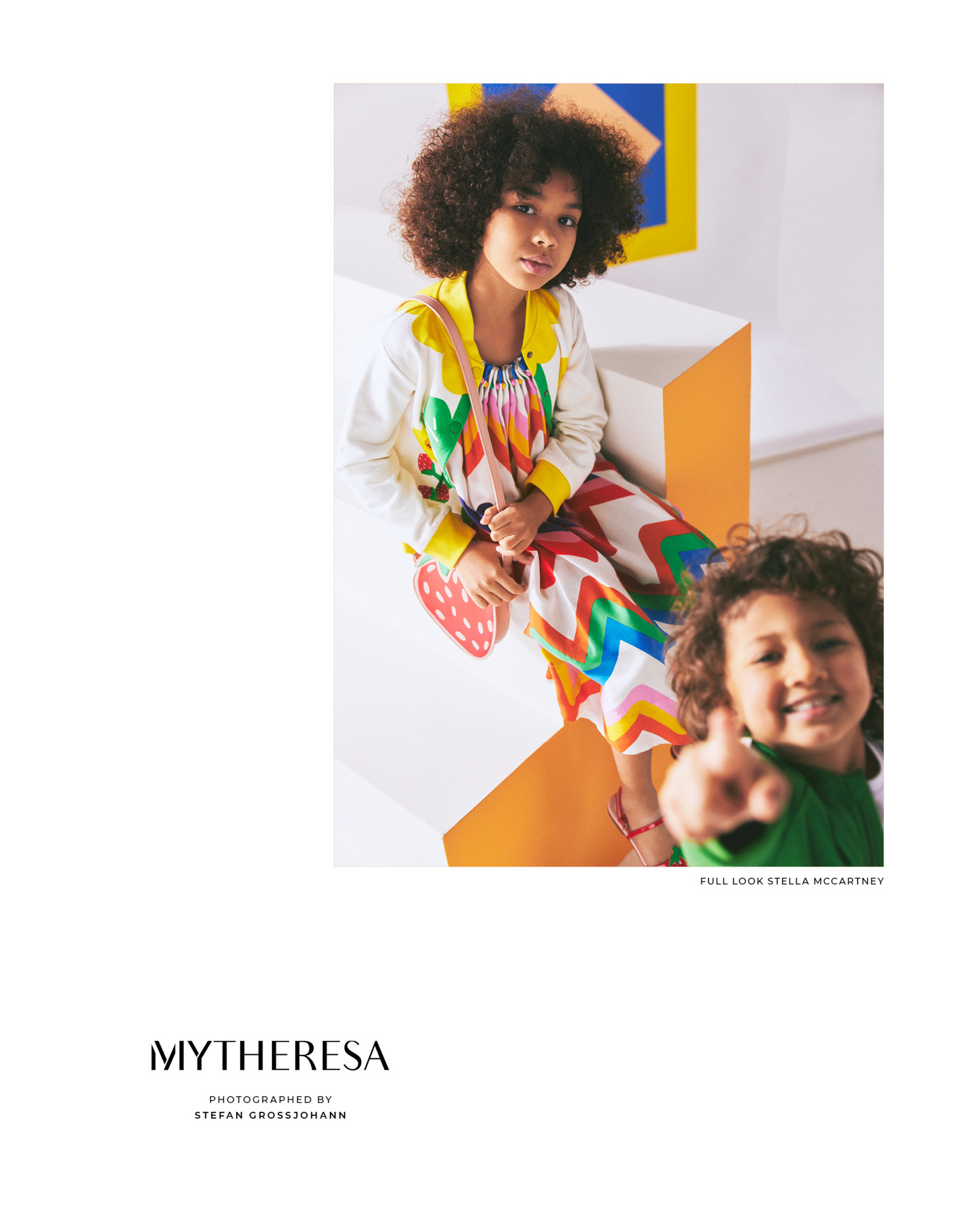 two children are posing in front of an advertisement for mythesa