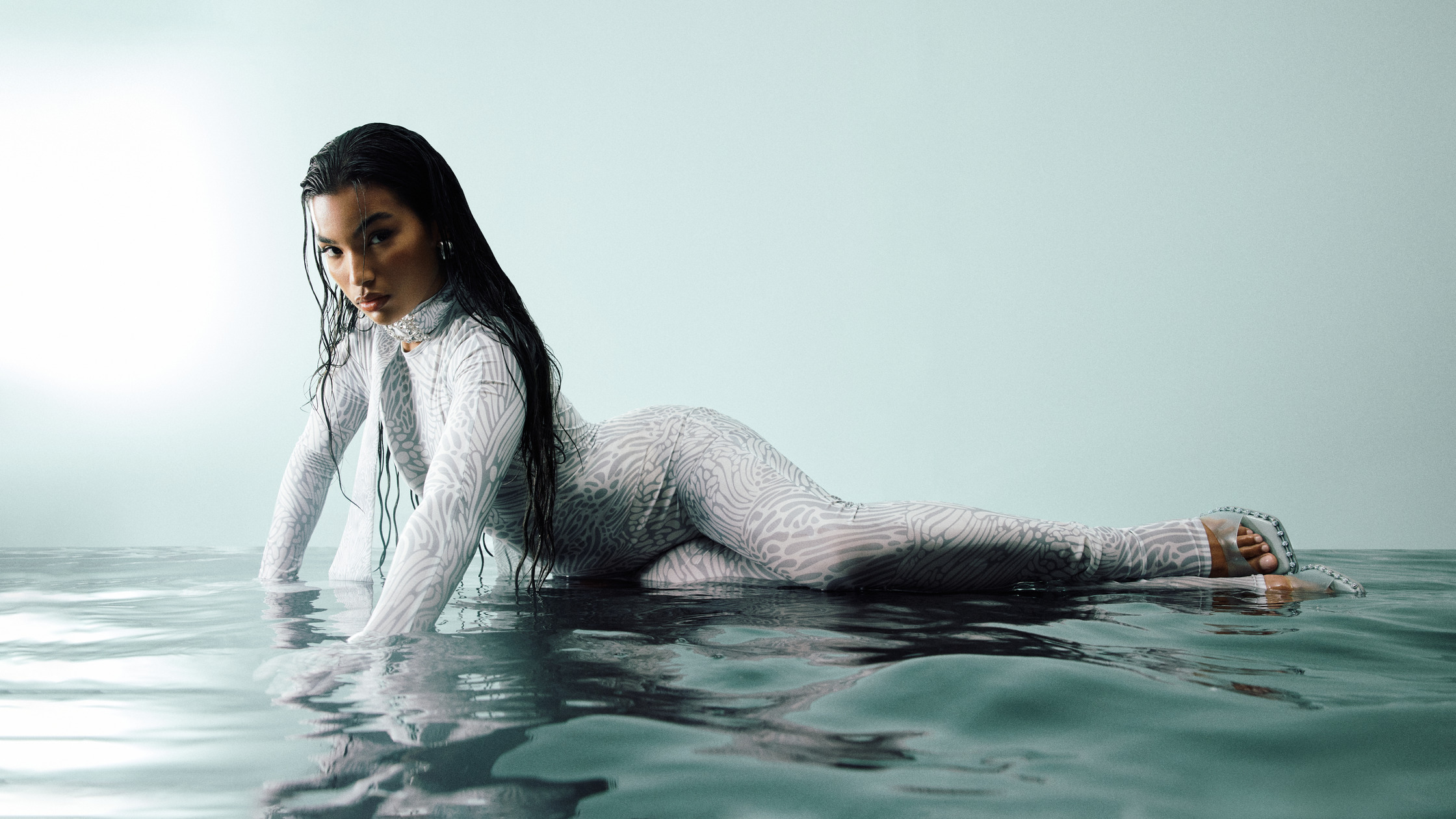a woman in a silver bodysuit laying in water