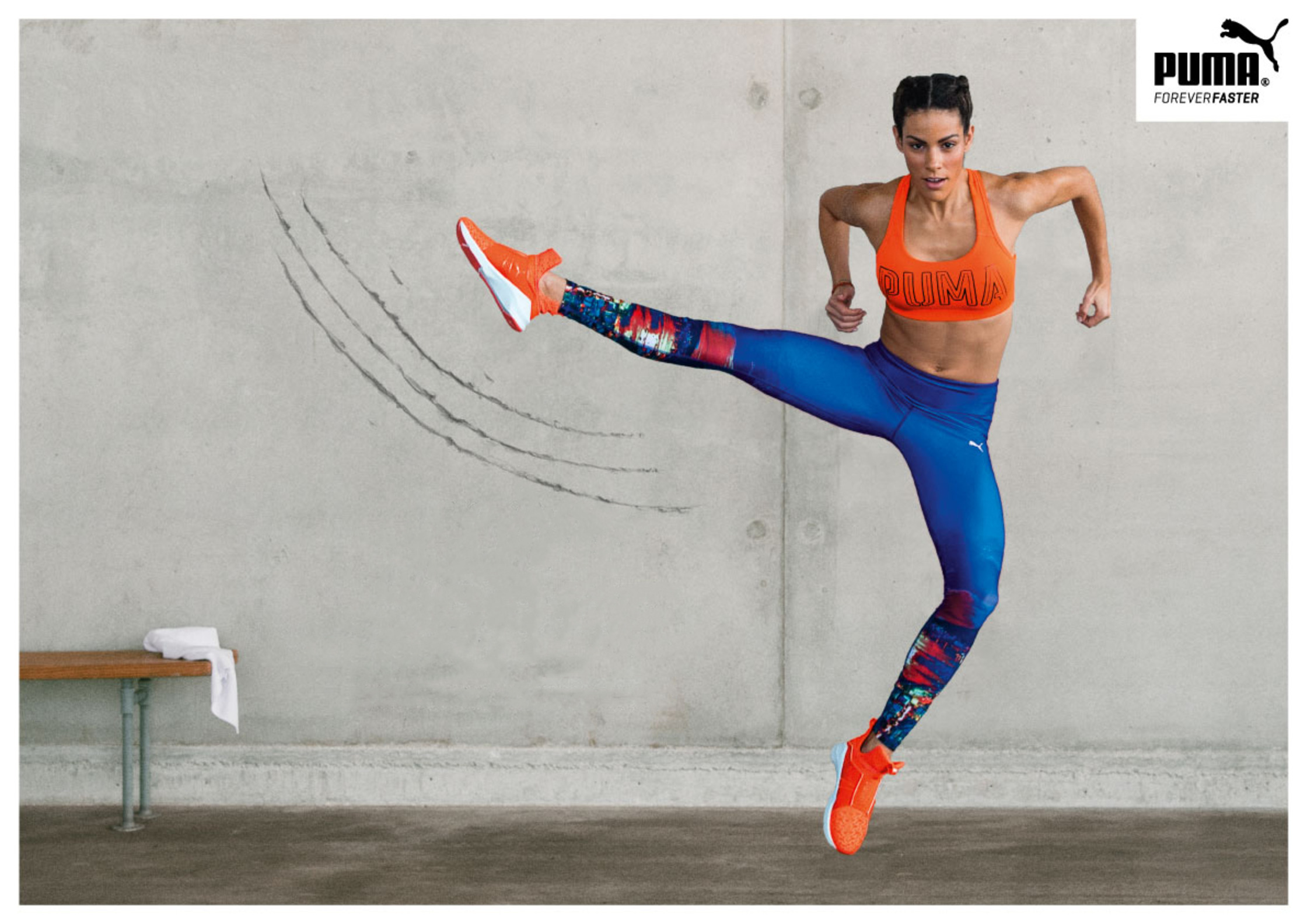 a woman in blue and orange jumps in the air puma