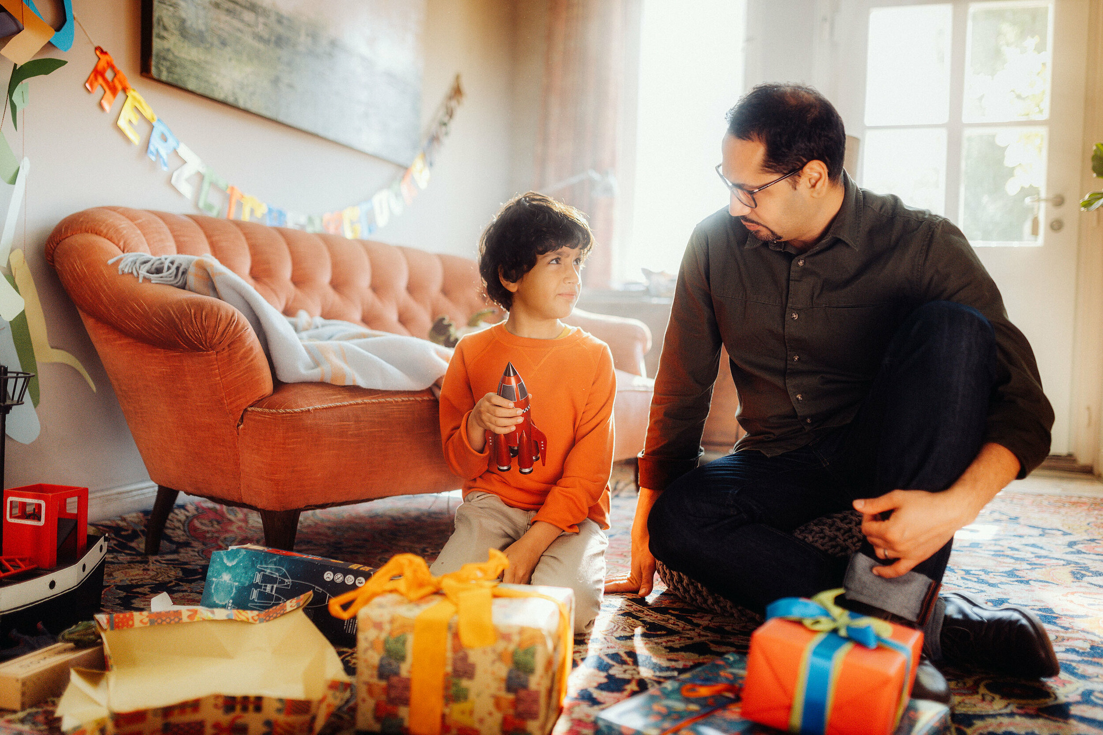a man and his son are playing with presents in a living room