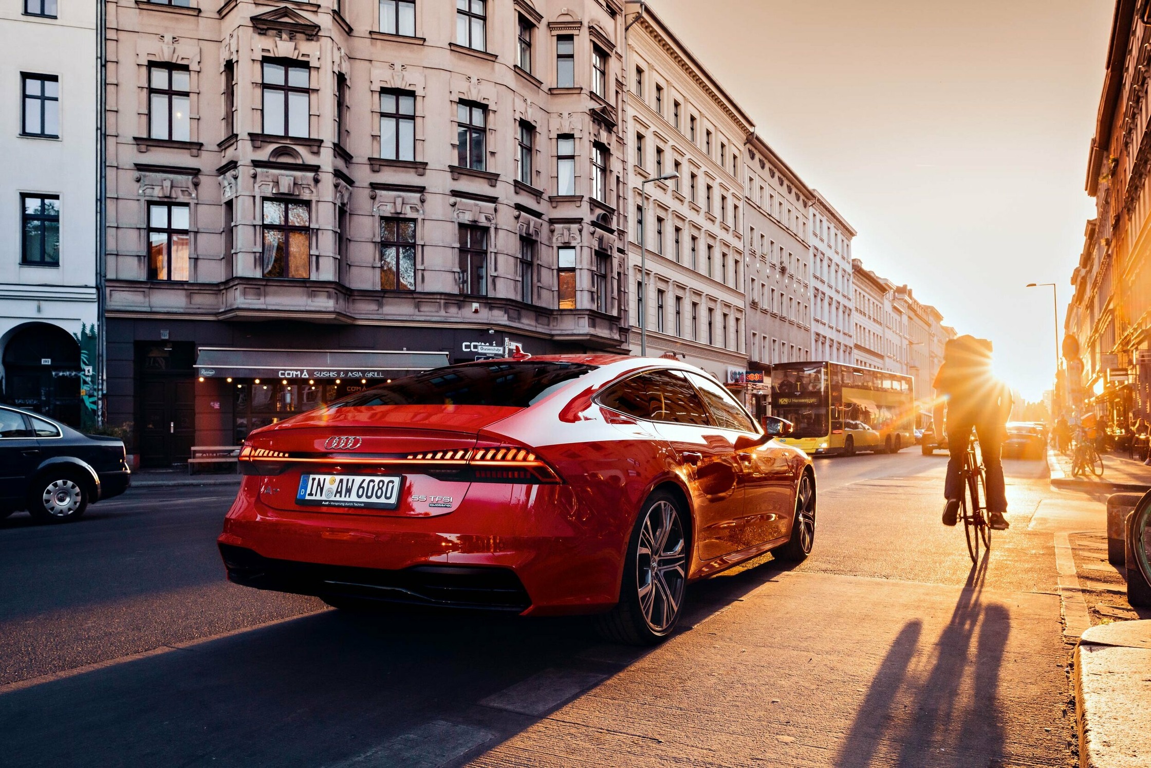 a red audi s7 on a city street at sunset