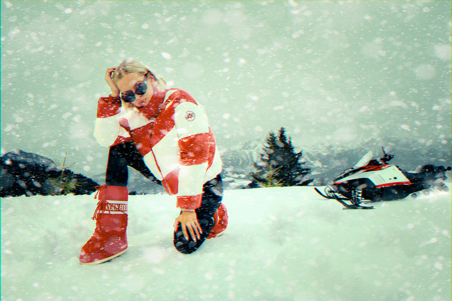 a woman kneeling in the snow next to a snowmobile