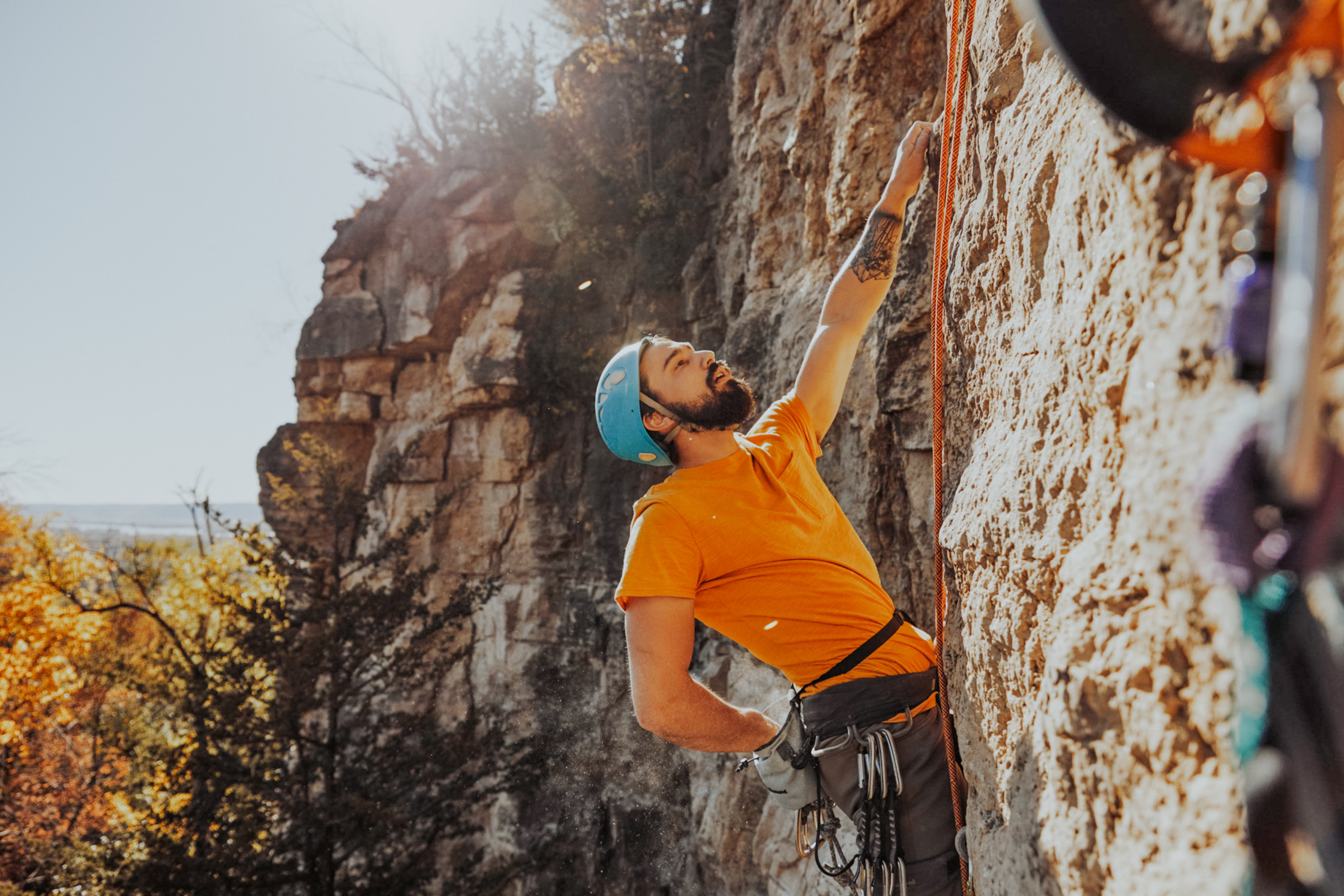 a man in an orange shirt is climbing a rock wall