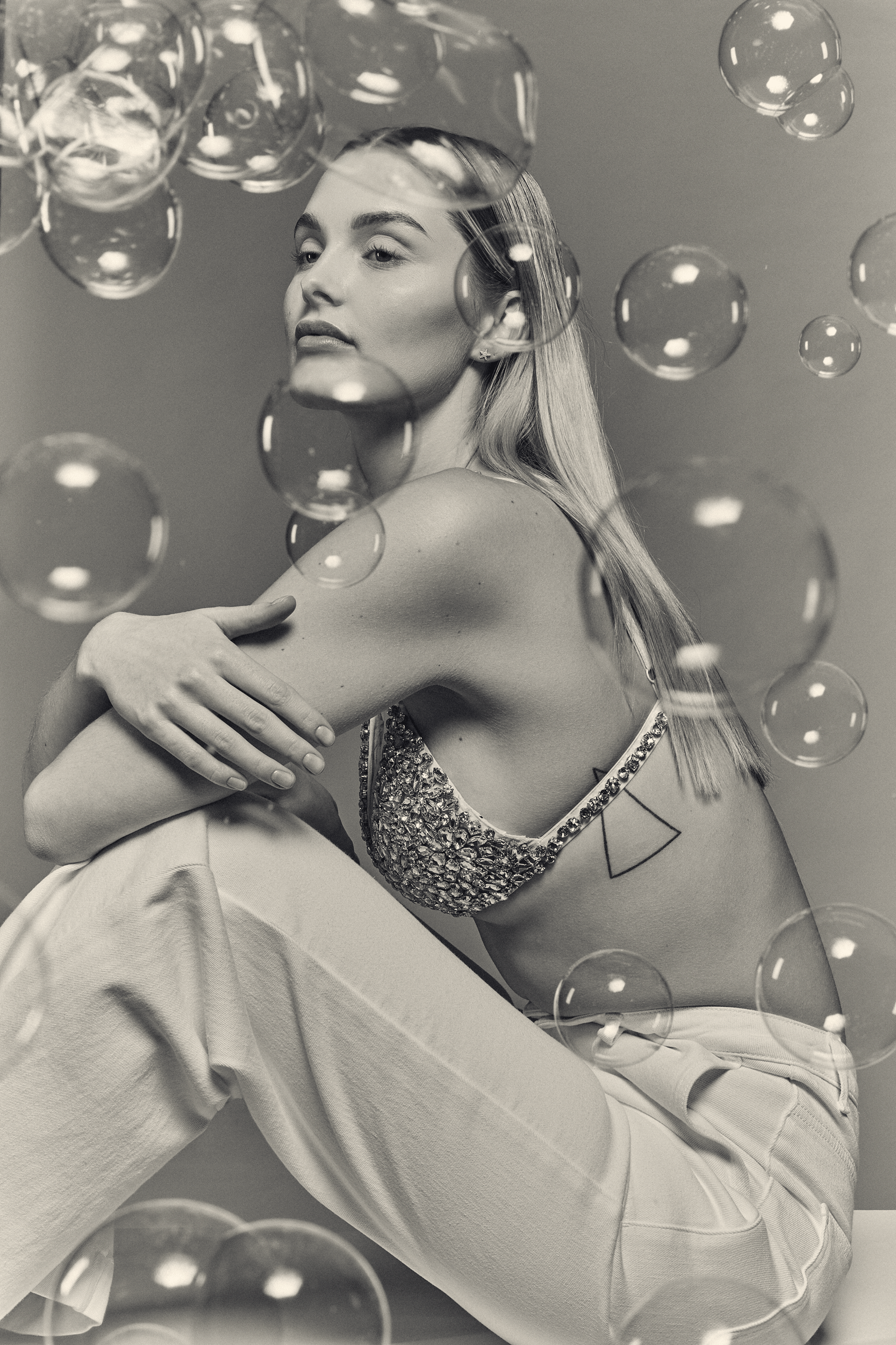 a woman in a bikini sitting inbetween  soap bubbles by photographer Frauke Fischer